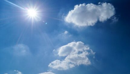 Grand soleil dans un ciel bleu avec deux nuages